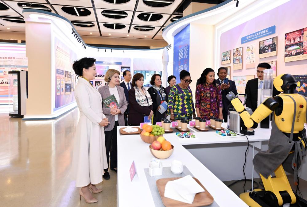 Peng Liyuan (L), wife of Chinese President Xi Jinping and UNESCO special envoy for the advancement of girls' and women's education, together with domestic and international guests, visits an exhibition showcasing China's progress in digital and intelligent empowerment for women and girls in Beijing, China, October 14, 2025. /Xinhua